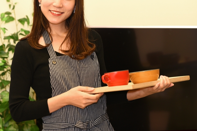 料理を運ぶエプロン姿の女性