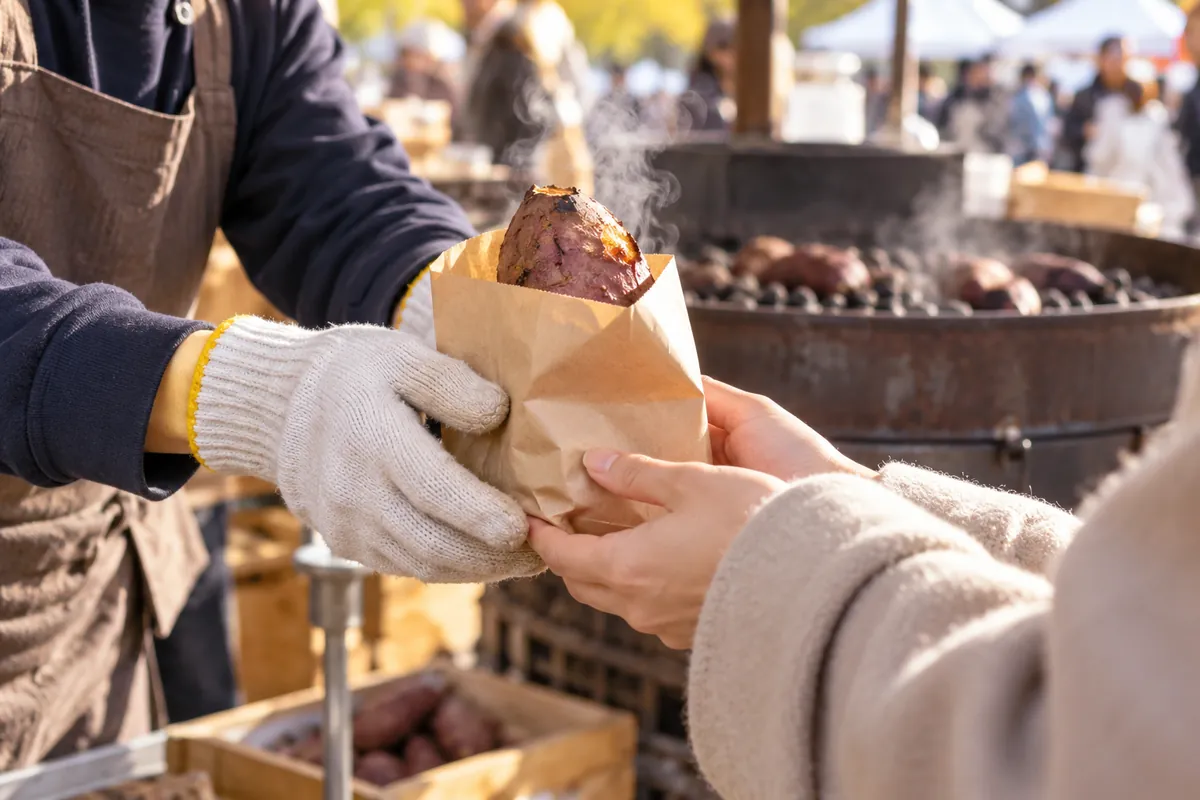 丸ごと焼いた焼き芋を紙袋に入れて手渡す様子
